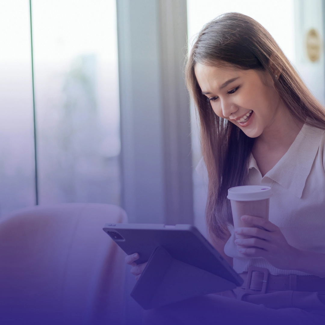 A lady looking at tablet while holding a cup of coffee